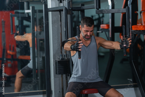 Mature trainer athlete working out chest muscles doing strength training exercises on gym benchpress equipment.