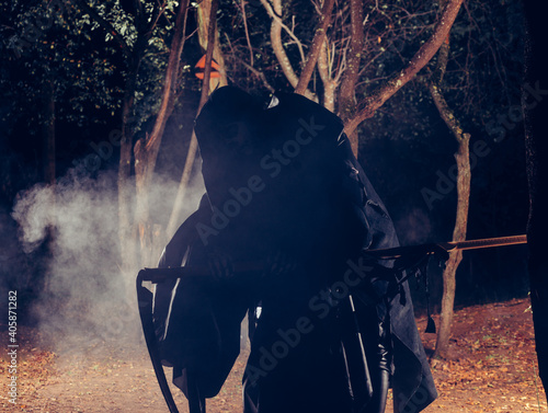 Grim Reaper standing in the fog at night with his scythe. photo