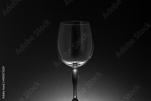 Tallo y cáliz de una copa de cristal vacía sobre fondo negro con iluminación posterior, en clave baja.