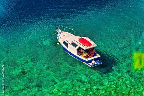 A man is sitting in a little boat and fishing in the sea during summer day. © Goran