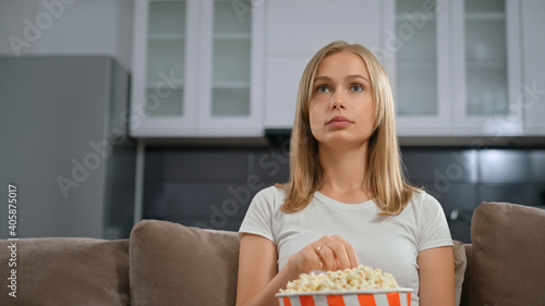 Blonde enjoy watching movie with popcorn.