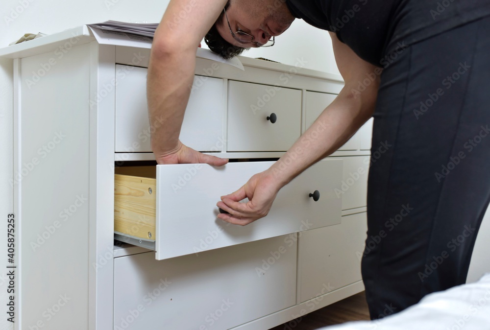 man assembles drawers of new furniture