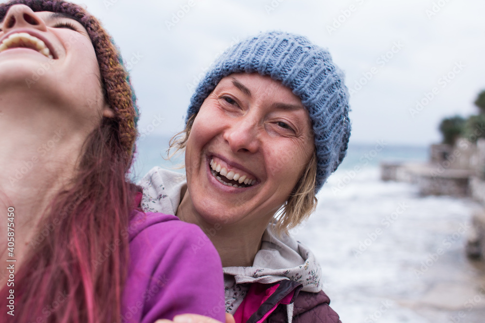 two girls laugh on the beach while walking two girls laugh on the beach while walking