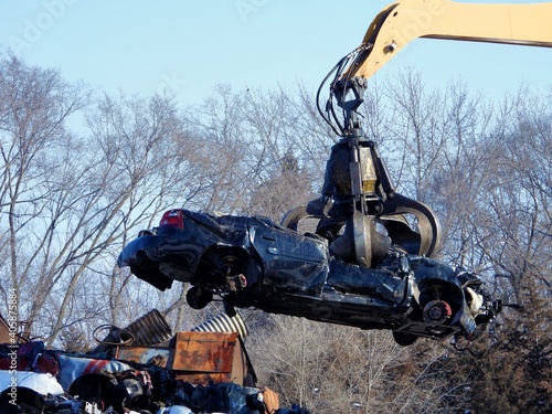 Photography Junkyard crane with claw moving crushed car