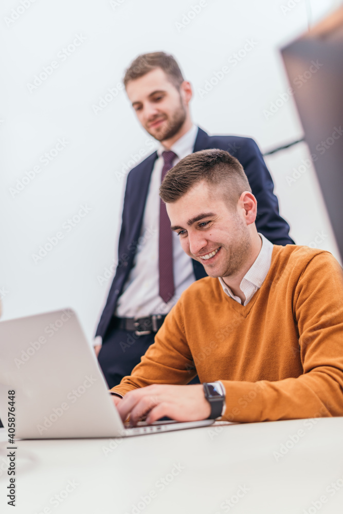 Picture of a businessman working on some final financial details with a suited manager standing next to him Picture of a businessman working on some final financial details with a suited manager standing next to him