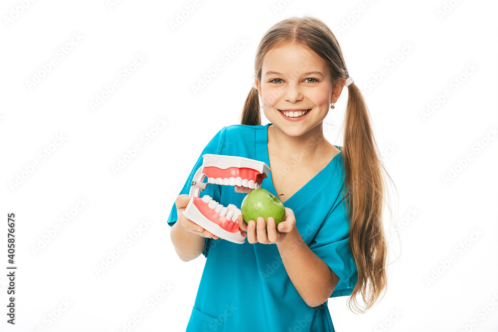 Child with a toothy smile, holding an anatomical model of teeth and apple in her hands. Fruits are very healthy for children's teeth Child with a toothy smile, holding an anatomical model of teeth and apple in her hands. Fruits are very healthy for children's teeth
