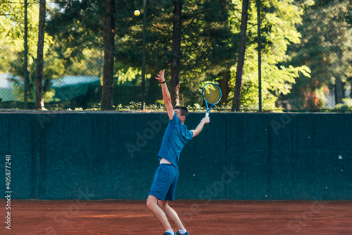 Professional equipped male tennis player beating hard the tennis ball with a forehand