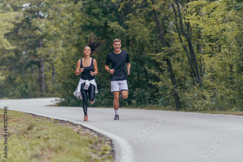 Young fit couple atheltes running on running road in a forest. © qunica.com