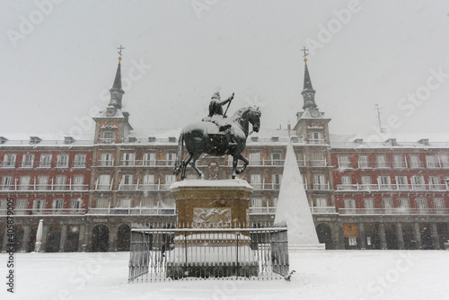 View of the historic Plaza Mayor of Madrid covered with snow under a heavy snowfall.