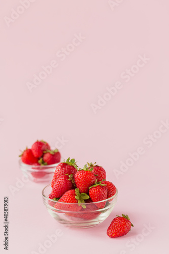 Healthy breakfast with ripe sweet berries. Fresh beauty strawberries in glass bowl on light pink background.