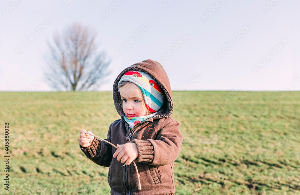 Toddler girl on dyke playing with stick