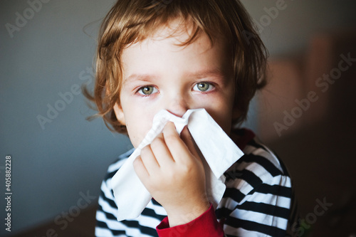 Canvas Print Cute little boy blowing his nose into a handkerchief.