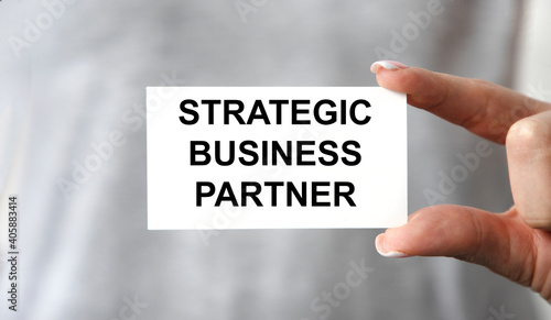 A girl holds a card with a strategic BUSINESS PARTNER.