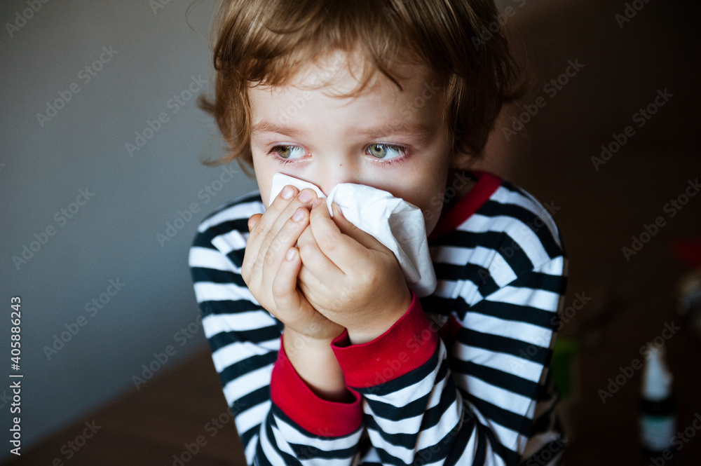Cute little boy blowing his nose into a handkerchief.