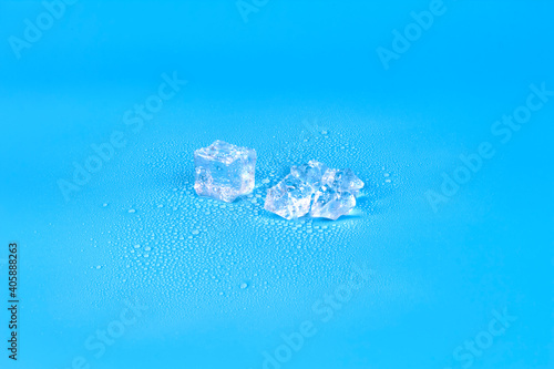 A broken cube of melting ice on a blue background