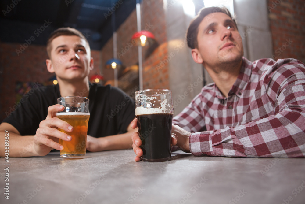 Two men watching game at beer pub together Two men watching game at beer pub together
