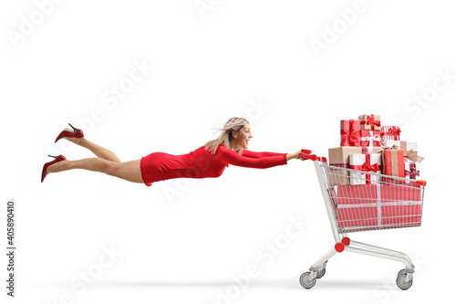 Attractive woman in a red dress flying with a shopping cart full of presents © Ljupco Smokovski