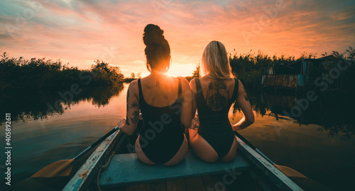 Ragazze con tatuaggi su una canoa in gita al lago al tramonto  photo