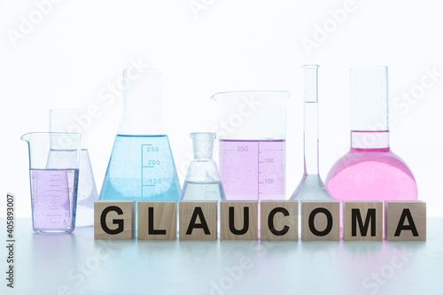 GLAUCOMA word written on a wooden cubes on the background with flasks filled with multicolored reagents. Medicine concept. Selective focus.