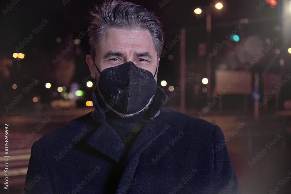 Covid-19 portrait - man in medical face mask on street in Winter. City lights at night. Covid-19 portrait - man in medical face mask on street in Winter. City lights at night.