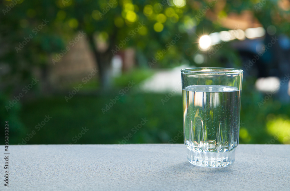 Drinking water glass against the background of green nature. Drinking water glass against the background of green nature.