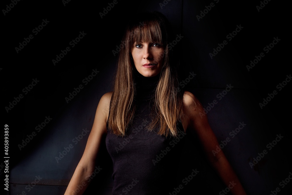 Beauty portrait of attractive young woman looking at camera, serious facial expression. Dark background. Beauty portrait of attractive young woman looking at camera, serious facial expression. Dark background.