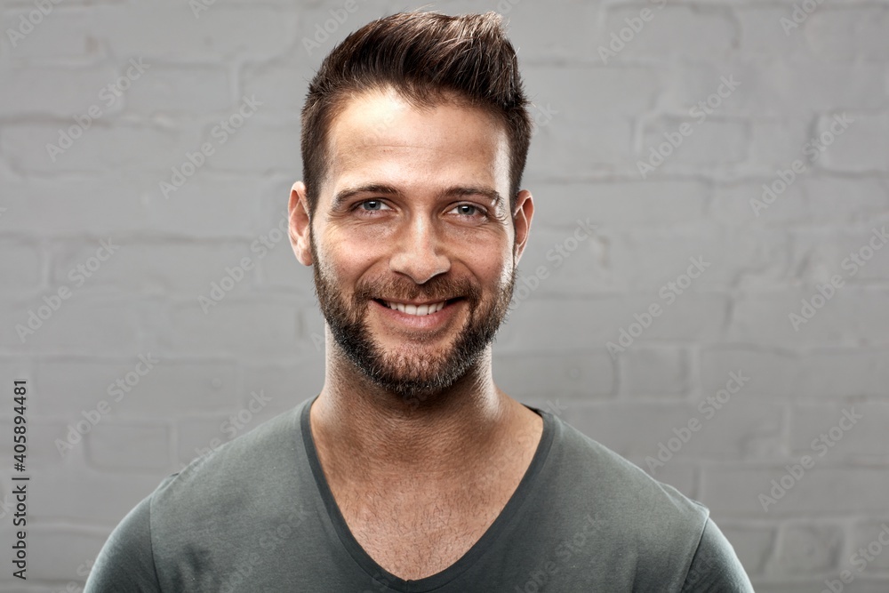 Portrait of happy young handsome man against white brickwall.
