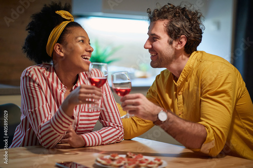 Happy mixed couple relaxing and drinking wine together