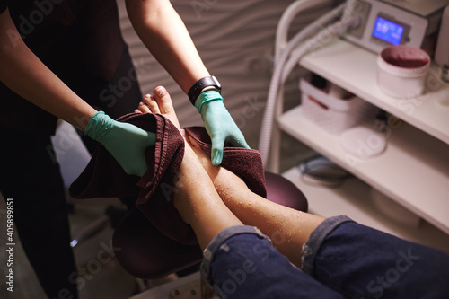 The pedicure master wipes the client's feet with a towel while making professional pedicure in beauty salon photo