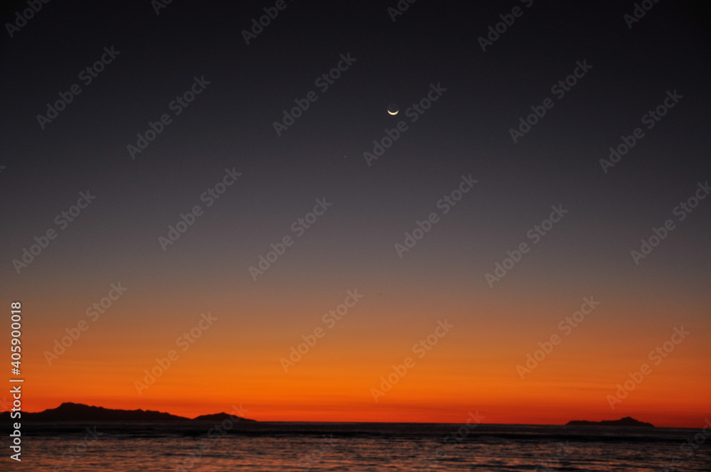 Red and dark dramatic sunset sky over the horizon water with the moon Red and dark dramatic sunset sky over the horizon water with the moon