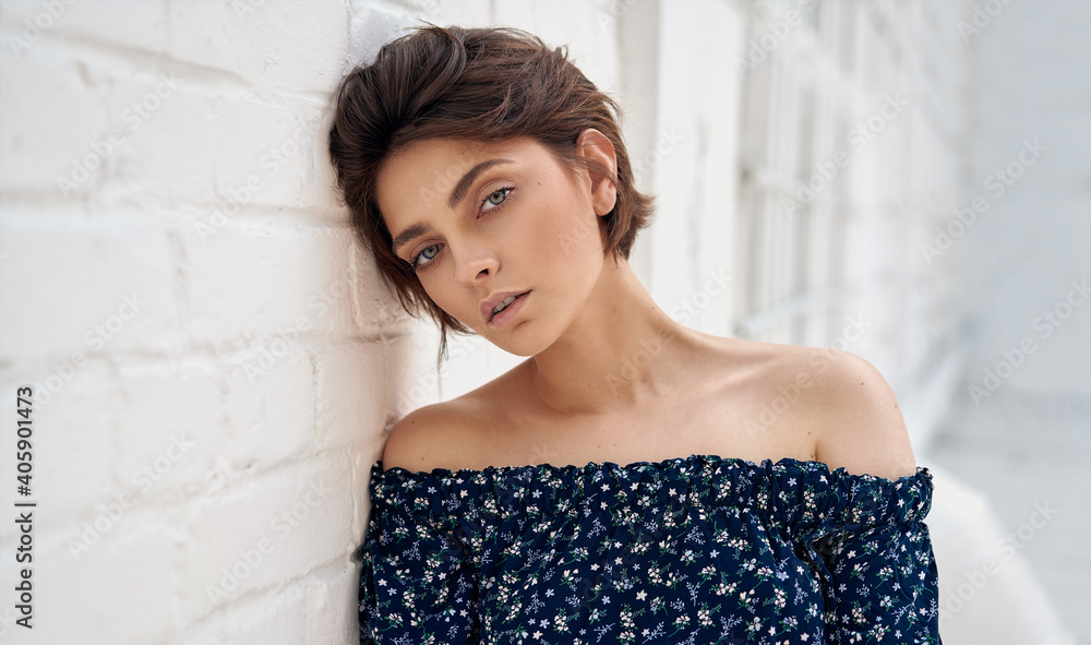 Fototapeta premium Beauty portrait of female face with natural clean skin and short hair on white wall