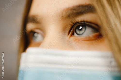 Macro eye view  Beautiful young woman with blue eyes wearing medical mask and looking away