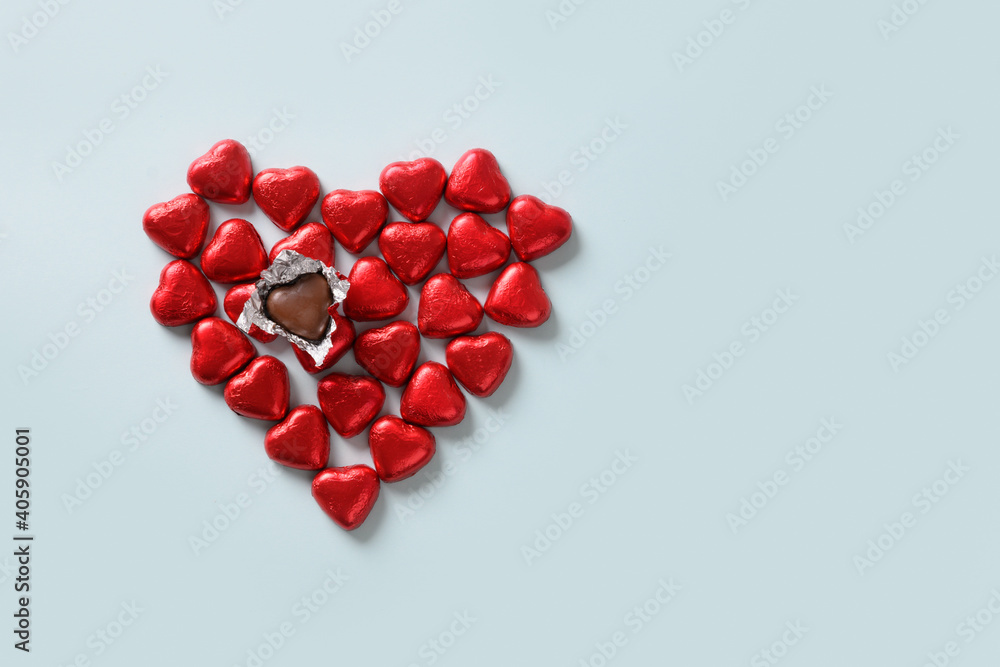 Red chocolate sweets as heart on blue background. Valentine's day concept. Red chocolate sweets as heart on blue background. Valentine's day concept.