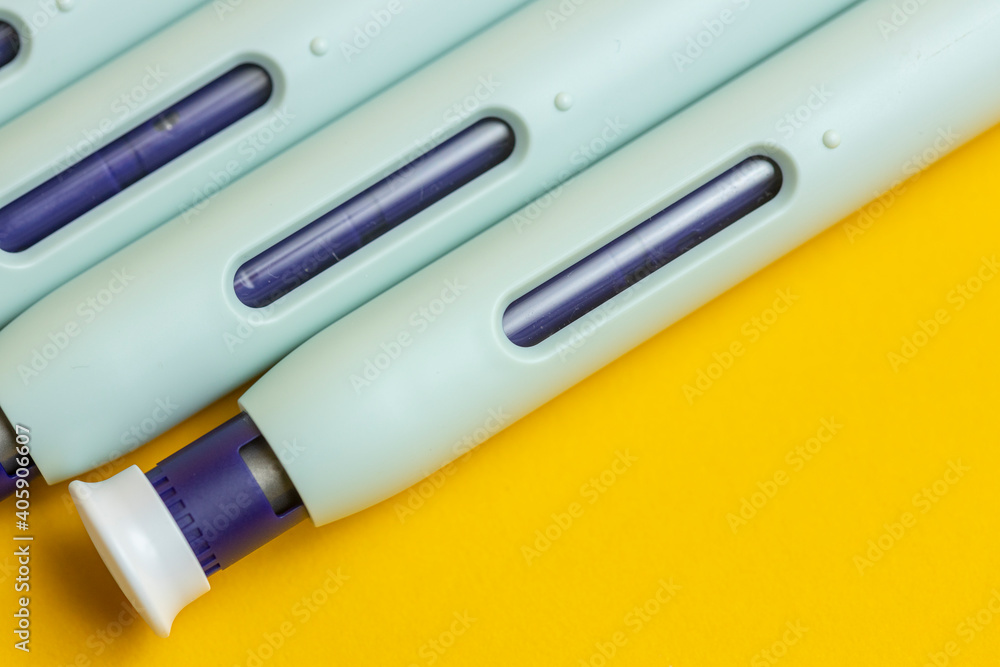 Macro closeup of syringe pen on seamless yellow background. Studio medical equipment still life concept. Macro closeup of syringe pen on seamless yellow background. Studio medical equipment still life concept.