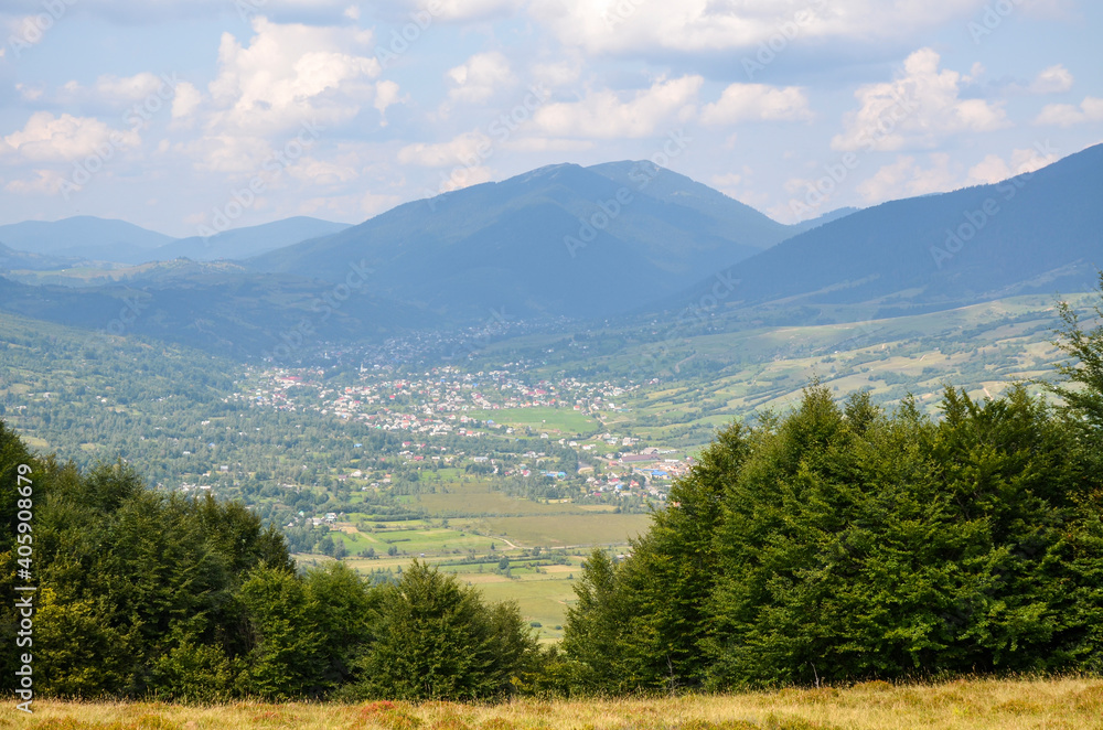 Obraz premium Beautiful landscape with forested hills and Carpathian village in the valley. Carpathian mountains in summer
