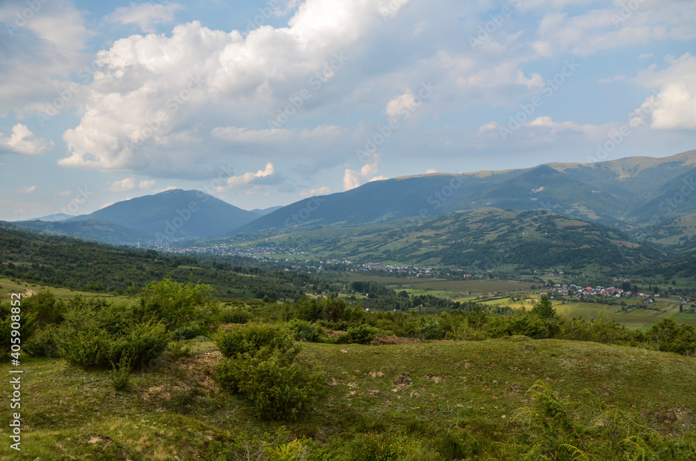 Beautiful landscape with forested hills and Carpathian village in the valley. Carpathian mountains in summer Beautiful landscape with forested hills and Carpathian village in the valley. Carpathian mountains in summer