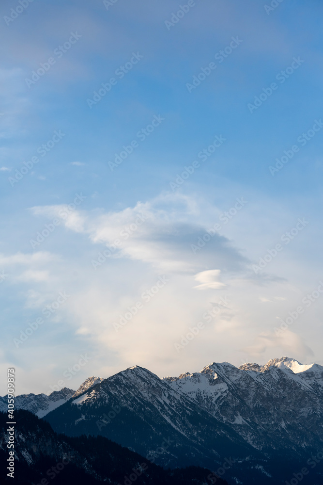 Mountain range around the Schwarzhanskarspitze mountain in vertical format in winter with gentle soft clouds and blue sky