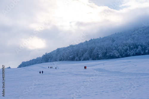 Wintersportler, Schneeschuhwanderer und Spaziergänger laufen durch eine sehr verschneite Landschaft in der Abenddämmerung