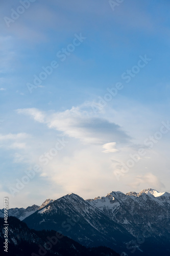 Mountain range around the Schwarzhanskarspitze mountain in vertical format in winter with gentle soft clouds and blue sky