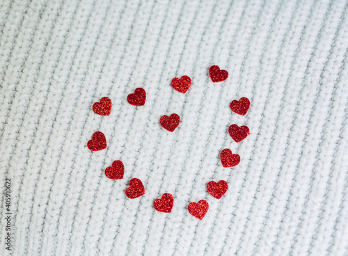 happy valentines day.red shiny hearts laid out in the form of a heart on a white knitted background. Red heart