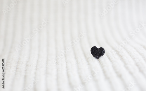 happy valentines day. black shiny heart on a white knitted background. space for text. 