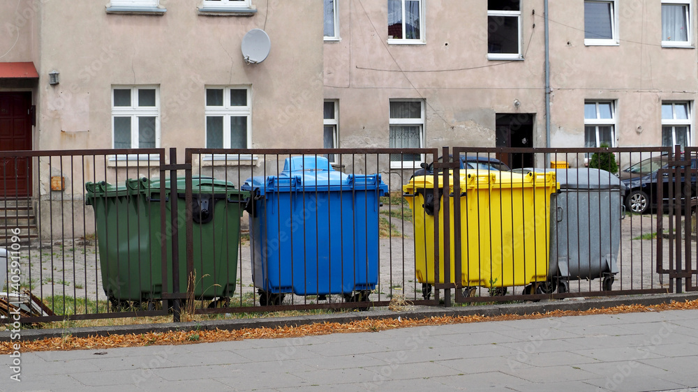 four plastic bins for sorting garbage against the background of a two-story old house and a black car four plastic bins for sorting garbage against the background of a two-story old house and a black car