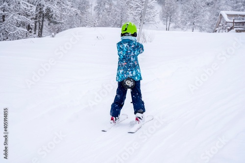 Blurred focus background. A girl lifting on the ski drag lift rope in blue sport outfit on the ski resort mountain do a ski lesson during a snowfall. Ski resort in french mountains.
