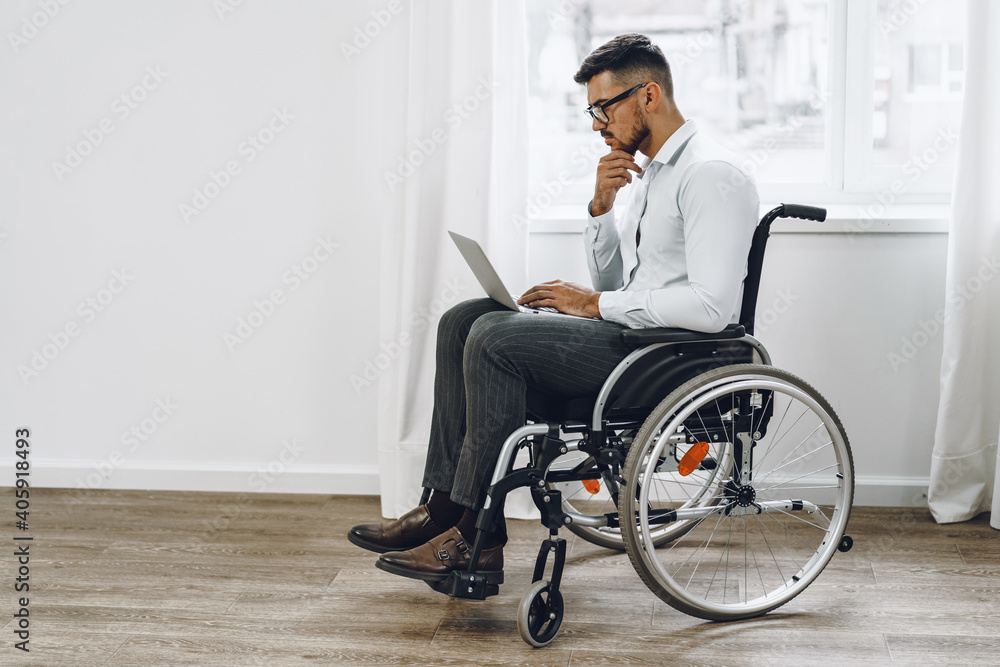 Businessman sitting in wheelchair and using laptop Businessman sitting in wheelchair and using laptop