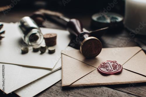Letter seal with wax seal stamp on the wood table. Vintage notary stamp and sealed envelope. Post concept. Sealing wax. Wax seal. Dark academia style. Scandinavian hygge styled composition.