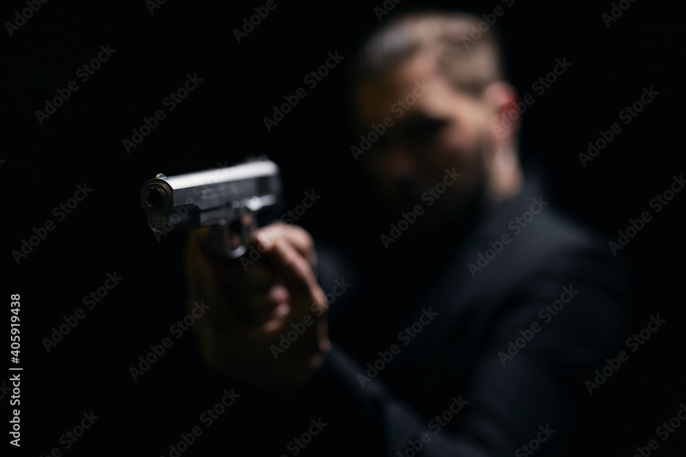 Blur background of gangster in black suit holding gun over black studio ...