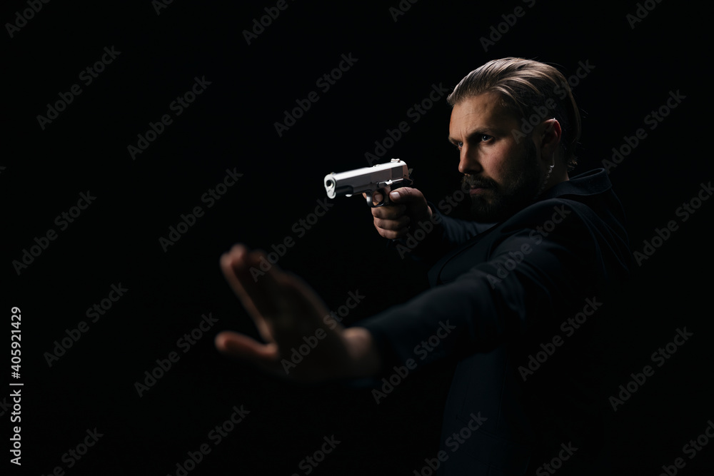 Confident bearded man in suit aiming with gun and showing sign stop ...