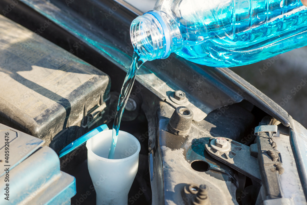 Automobile maintenance. Filling the windshield washer fluid on a car