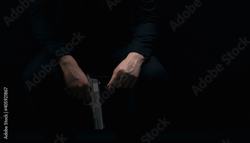 Close up of male hands holding weapon over black background. Gangster in suit holding gun in hands. Criminal lifestyle.