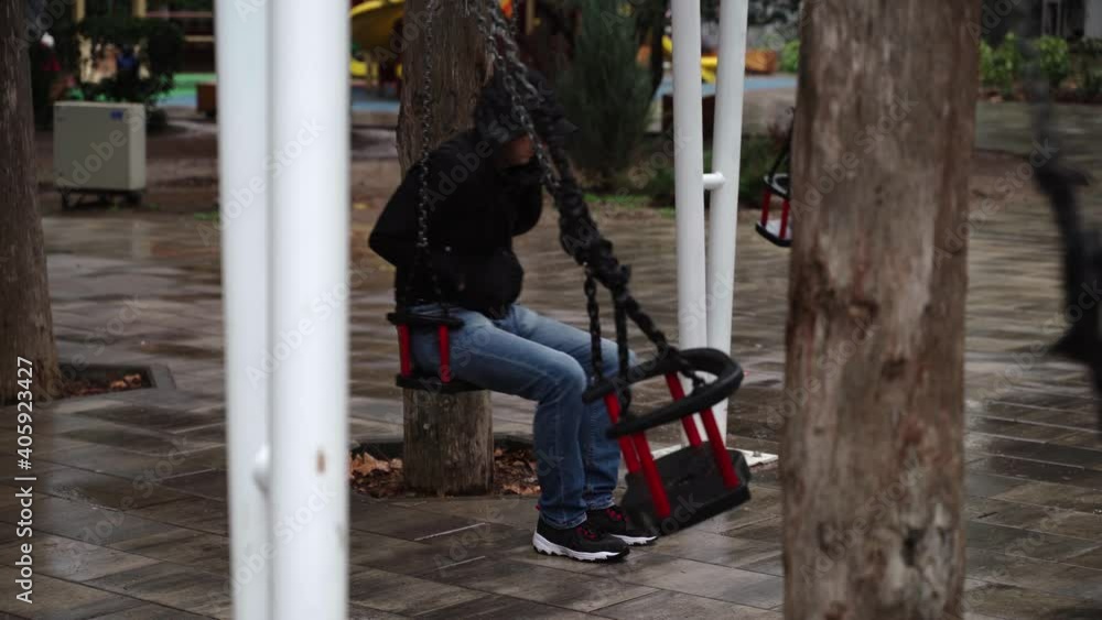 Lonely man in the park swinging on a swing. A sad man in depression is lonely swinging on a swing in an empty winter park. Lonely man in the park swinging on a swing. A sad man in depression is lonely swinging on a swing in an empty winter park.